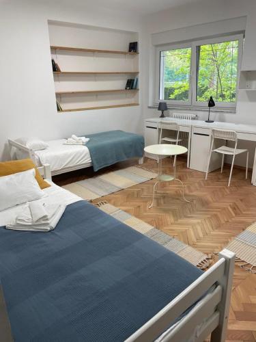 a bedroom with a bed and a desk and a kitchen at At the Burkulis' in Ljubljana
