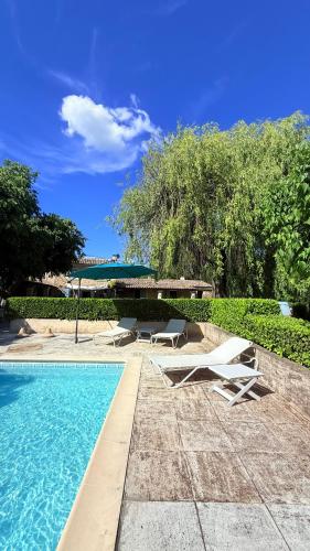 - une piscine avec 2 chaises longues et un parasol dans l'établissement Ateliers créatifs, à Puyvert