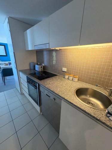 a kitchen with a sink and a counter at Oaks Glenelg Balcony Apartment in Glenelg