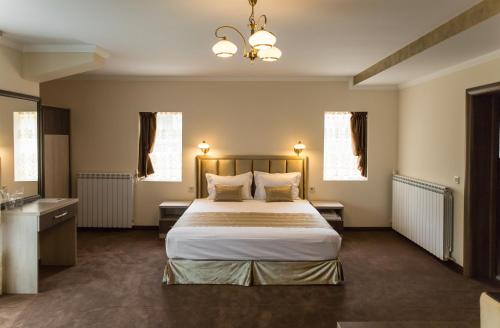 a bedroom with a large bed and two windows at Emmar Zlatograd in Zlatograd