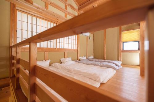 two beds in a room with wooden floors at ホタル屋 in Takashima