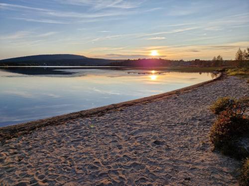 a sunset on the shore of a body of water at Holiday Home Ylläs-helmi - loistosijainti! in Äkäslompolo