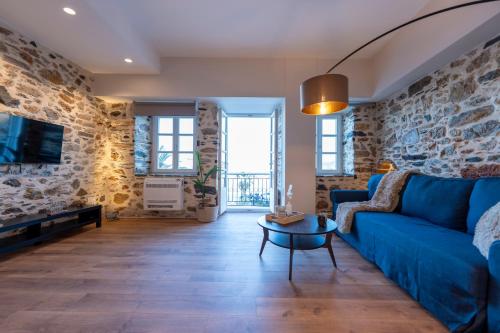 a living room with a blue couch and a stone wall at Casita in Ermoupoli