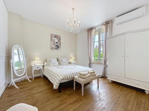Habitación blanca con cama y lámpara de araña. en Charmante maison 2 chambres avec cour et jardin, en Sainte-Savine