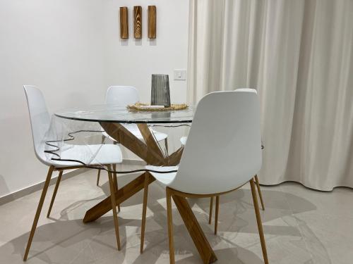a dining room with a glass table and white chairs at Palazzo Tilde in Marsala