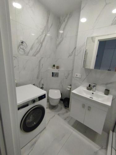 a white bathroom with a toilet and a sink at Tina's home in Batumi