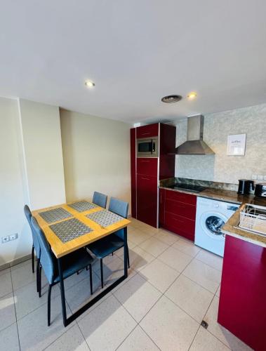 a kitchen with a table and a kitchen with red cabinets at Hermoso piso en un paso de la Playa de Fenals con piscina in Lloret de Mar