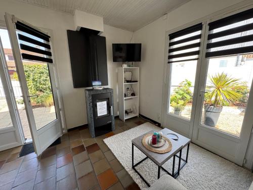 un salon avec une télévision et une table dans l'établissement Maison Spacieuse tout près de La Mer, à La Tranche-sur-Mer