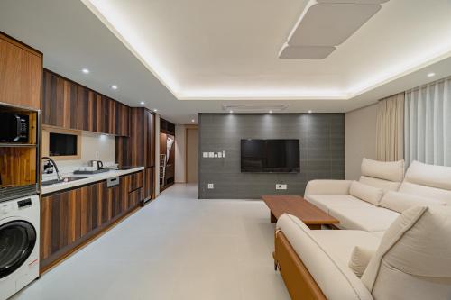 a living room with a couch and a kitchen at Masion Sanbang Jeju in Seogwipo