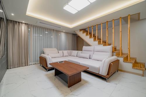 a living room with a white couch and a wooden table at Masion Sanbang Jeju in Seogwipo
