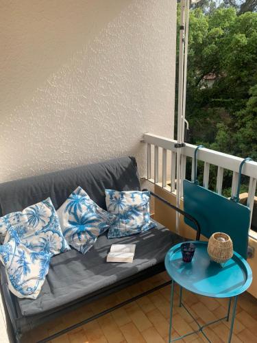 d'un canapé avec des oreillers sur un balcon avec une table. dans l'établissement Studio calme 4 personnes 400 m de la plage sur la presqu'île de St mandrier proche toulon, à Saint-Mandrier-sur-Mer