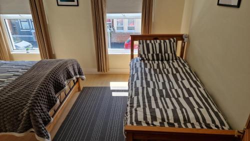 two twin beds in a room with a window at Titanic History Private Home in Belfast