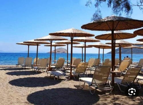 a group of chairs and umbrellas on a beach at SeaTerra Boutique suite in Kalamos