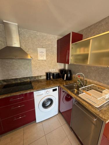 a kitchen with a washing machine and a sink at Hermoso piso en un paso de la Playa de Fenals con piscina in Lloret de Mar