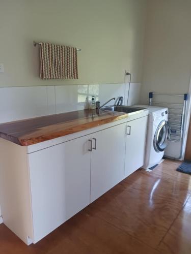 a white kitchen with a sink and a washing machine at Mission Beach Rural Escape in Mission Beach