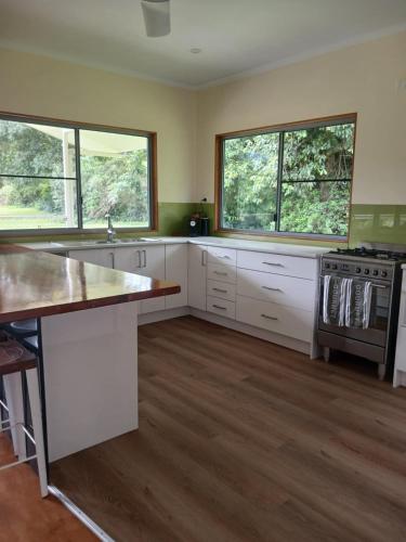 a large kitchen with white cabinets and windows at Mission Beach Rural Escape in Mission Beach