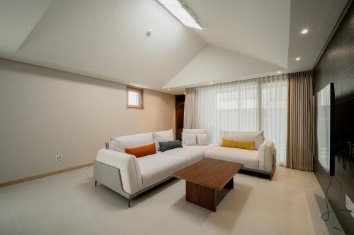 a living room with two white couches and a table at Masion Sanbang Jeju in Seogwipo