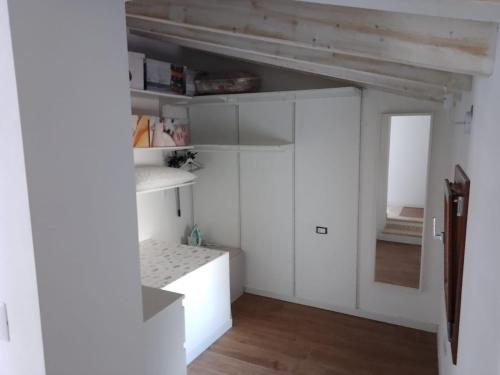a kitchen with white cabinets and a wooden floor at Civico 381 - private parking in Quartu SantʼElena