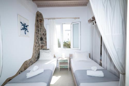 two beds in a room with two windows at Almyra Home in Ornos