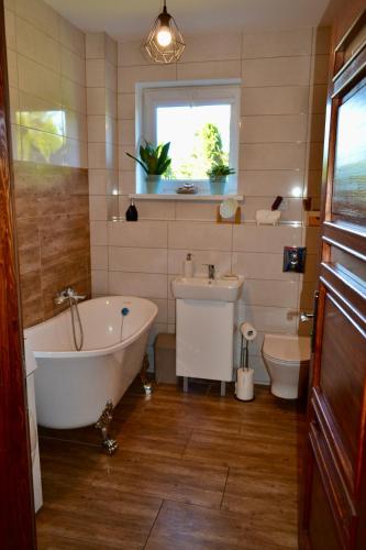 a bathroom with a tub and a toilet and a sink at Noclegi Bero Fejn in Lipusz