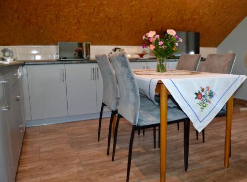 a kitchen with a table with chairs and a vase of flowers at Noclegi Bero Fejn in Lipusz