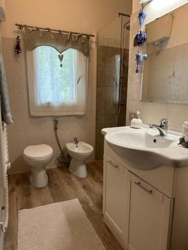 a bathroom with a sink and a toilet and a window at C & C in Valdobbiadene