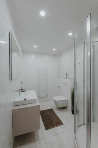 a white bathroom with a sink and a toilet at Contessa Apartments in Košice