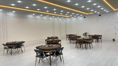 a room with tables and chairs and a white wall at Chinor Hotel Fergana in Fergana