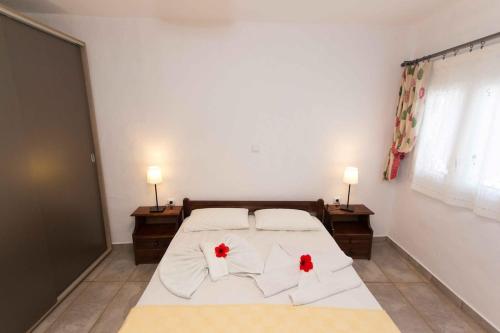 a bedroom with a bed with two red flowers on it at PAROS APARTMENT MELAS b1 in Parikia