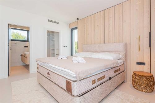 a bedroom with a large bed with two towels on it at Villa Serena Luxury Seafront Escape with Pool in Privlaka