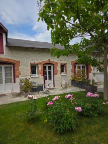 une maison avec des fleurs roses dans la cour dans l'établissement La Renardière, à Bourges
