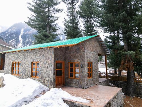 a small stone house with a green roof at Celine Resorts Kumrat Valley in Tāl