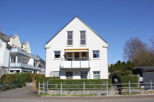 a white house with a balcony on a street at Ferienwohnung HeilbadOase in Erwitte
