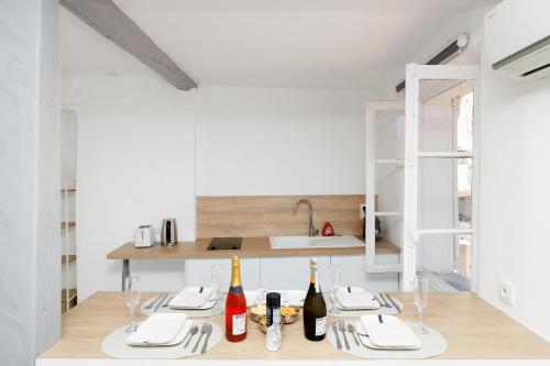 une cuisine avec des murs blancs et une table avec des bouteilles de vin dans l'établissement Renoveted studio - Central - AC, à Cannes