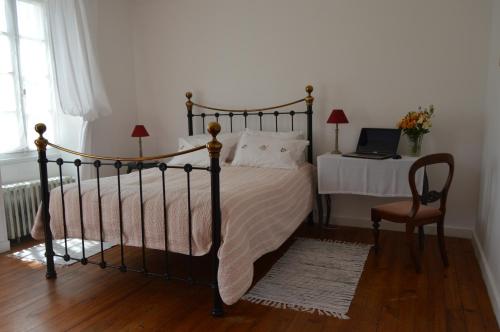 a bedroom with a bed and a desk with a laptop at La Vieille Distillerie in Le Tâtre