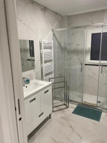 a white bathroom with a shower and a sink at homeSilvaSanches in Quinta do Conde