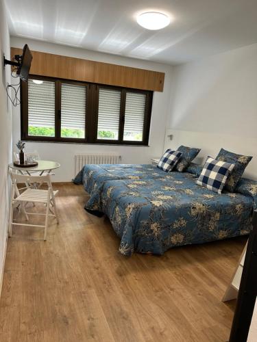 a bedroom with a bed and a table and windows at El Malecon in Sarria