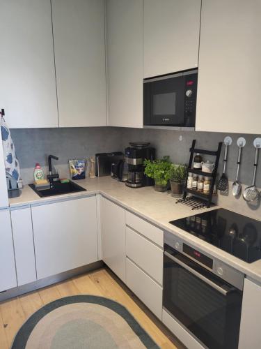 a kitchen with white cabinets and a black stove top oven at Valgre Residence 7th Floor in Pärnu