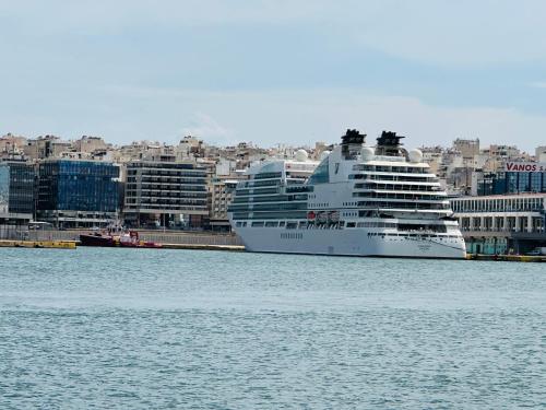 a cruise ship in the water with a city in the background at Royal Red suite No2 PIRAEUS PORT in Piraeus
