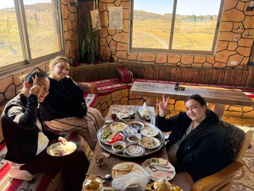 a group of three women sitting at a table with food at Dana bedouin Sky in Dana