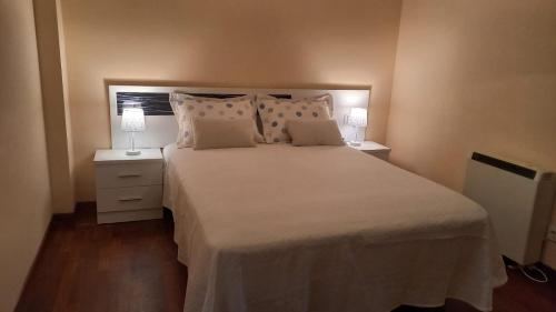 Un dormitorio con una gran cama blanca con dos lámparas. en Vacaciones, en Cedeira