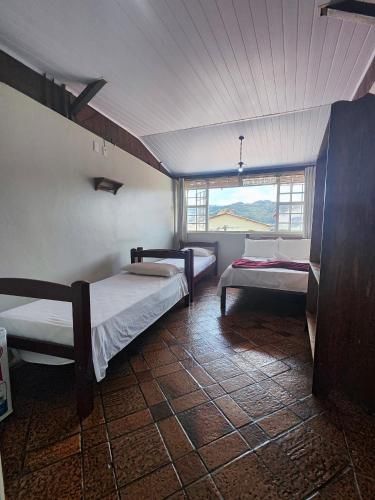 a room with two beds and a window at Pousada Acayaca in Diamantina