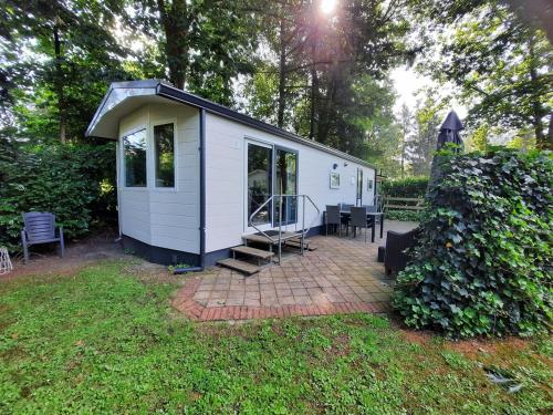a white tiny house in the middle of a yard at Groene Oase in Epe