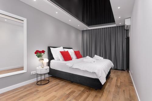 a bedroom with a bed with white and red pillows at Prestige Apartments Quorum - Apartamenty nad Odrą - 16 piętro in Wrocław