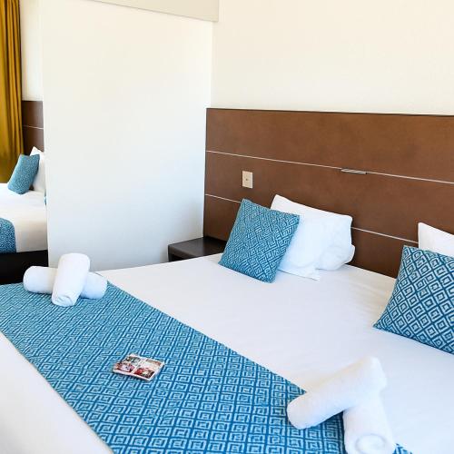 a hotel room with two beds with blue pillows at Hotel & Spa Gil de France Cap d'Agde in Cap d'Agde