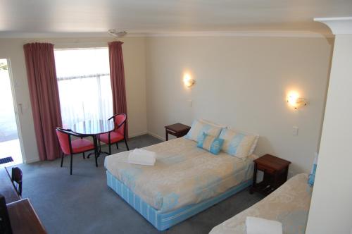 ein Hotelzimmer mit einem Bett, einem Tisch und einem Bett sowie einem Zimmer in der Unterkunft Elite Motor Inn in Armidale
