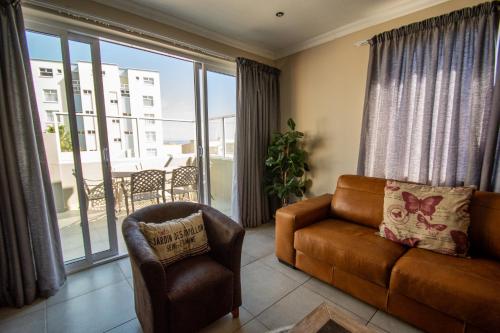 a living room with a couch and a chair and a balcony at Long Beach Selfcatering Namibia in Langstrand