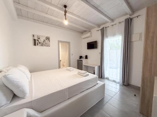 a white bedroom with a large bed and a window at Villa & Suite Elia Mykonos in Mikonos