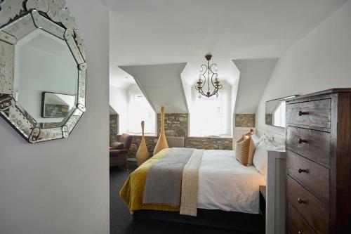 a bedroom with a bed with a dresser and a mirror at Monachyle Mhor Hotel in Lochearnhead