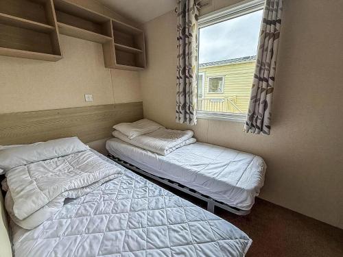two beds in a small room with a window at Great 6 Berth Caravan In Essex At St Osyth Beach Holiday Park Ref 28018Mv in Clacton-on-Sea